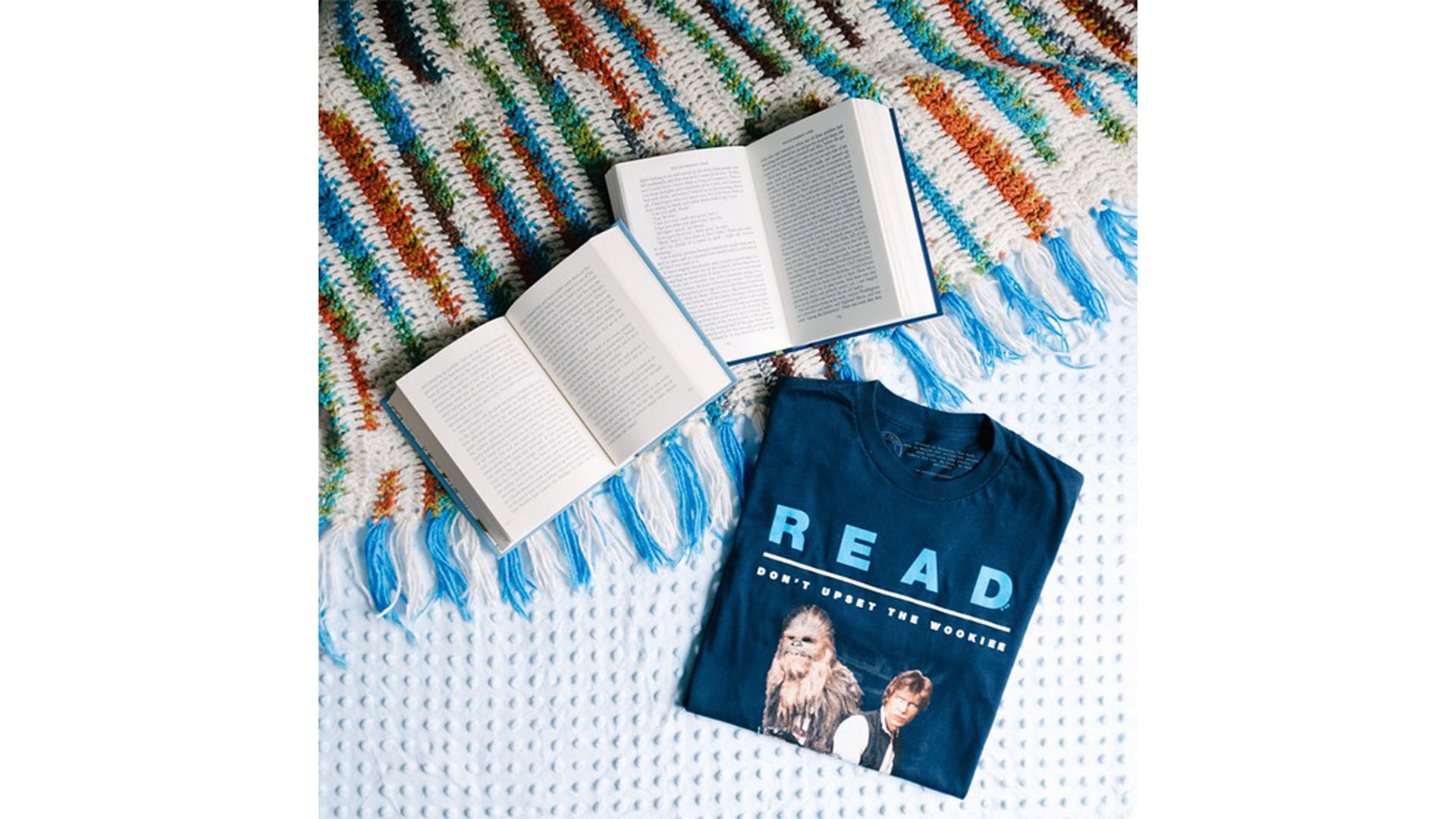 Two open books next to a folded navy blue t-shirt that says 
