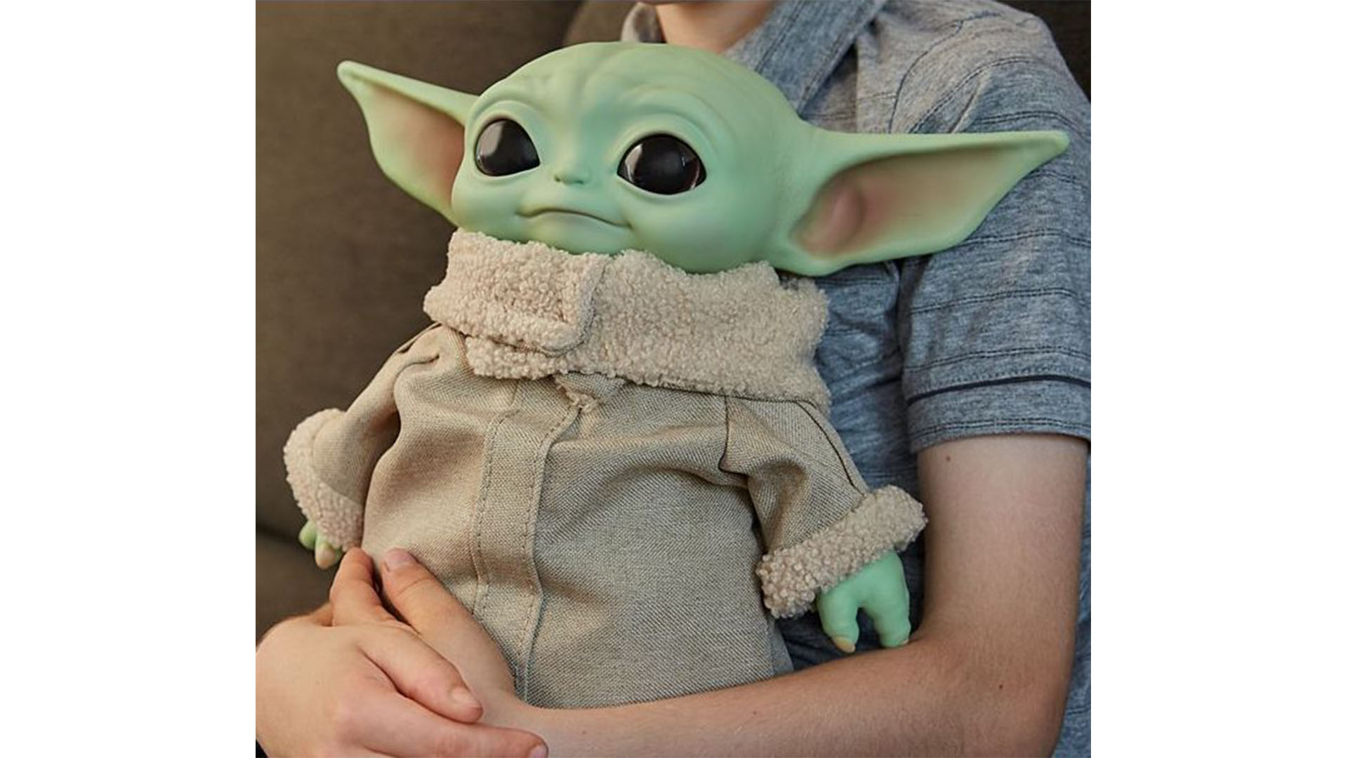 A close-up of a young person holding a life-sized Mattel plush of The Child from Star Wars: The Mandalorian.