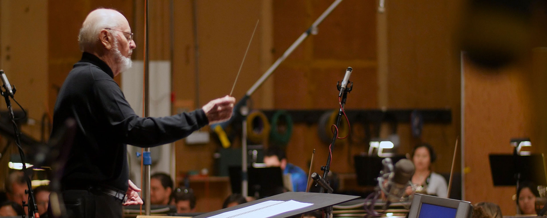 Composer John Williams conducts on a scoring stage.